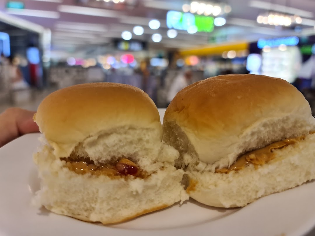 Two soft buns, one with peanut butter and jelly, the other with peanut butter, on a white plate.