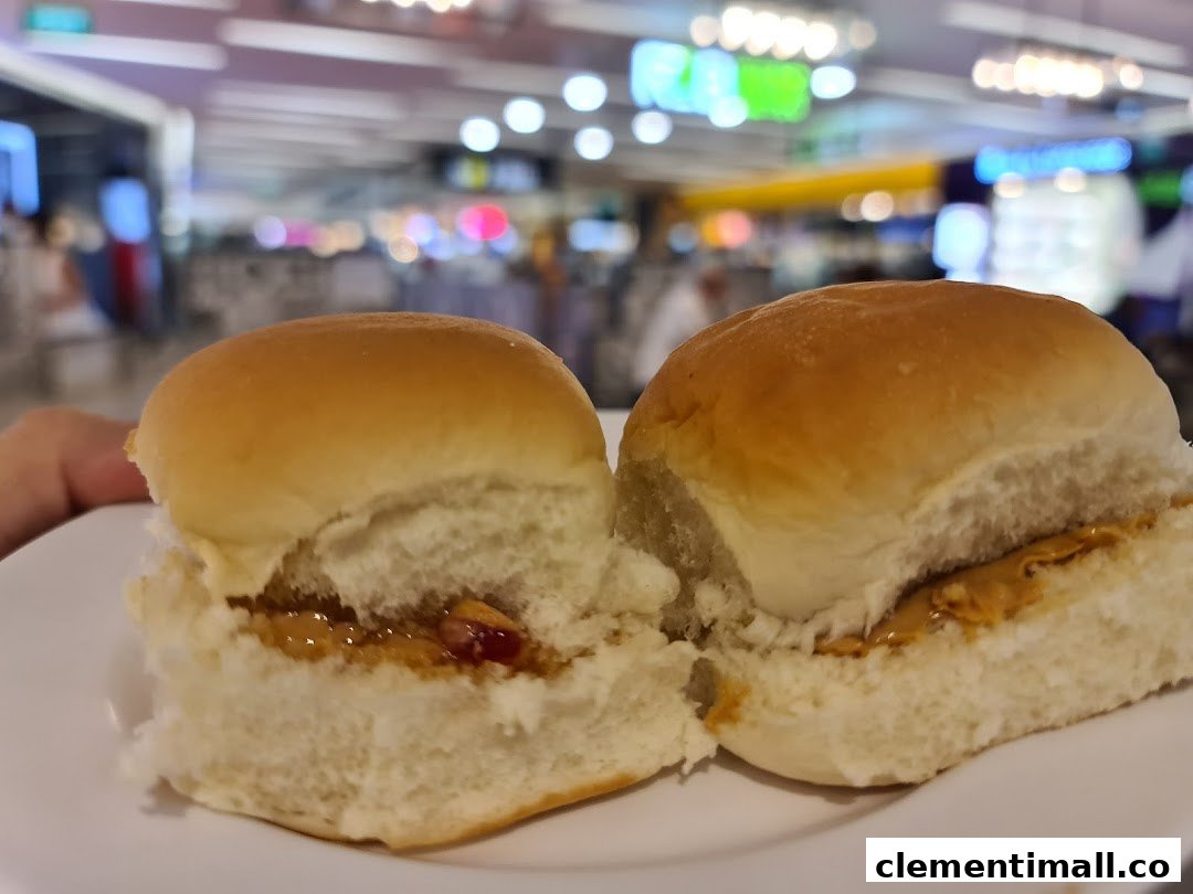 Two soft buns, one with peanut butter and jelly, the other with peanut butter, on a white plate.