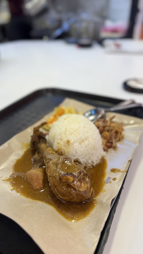 A delicious plate of chicken curry with rice and side dishes, served on a tray.