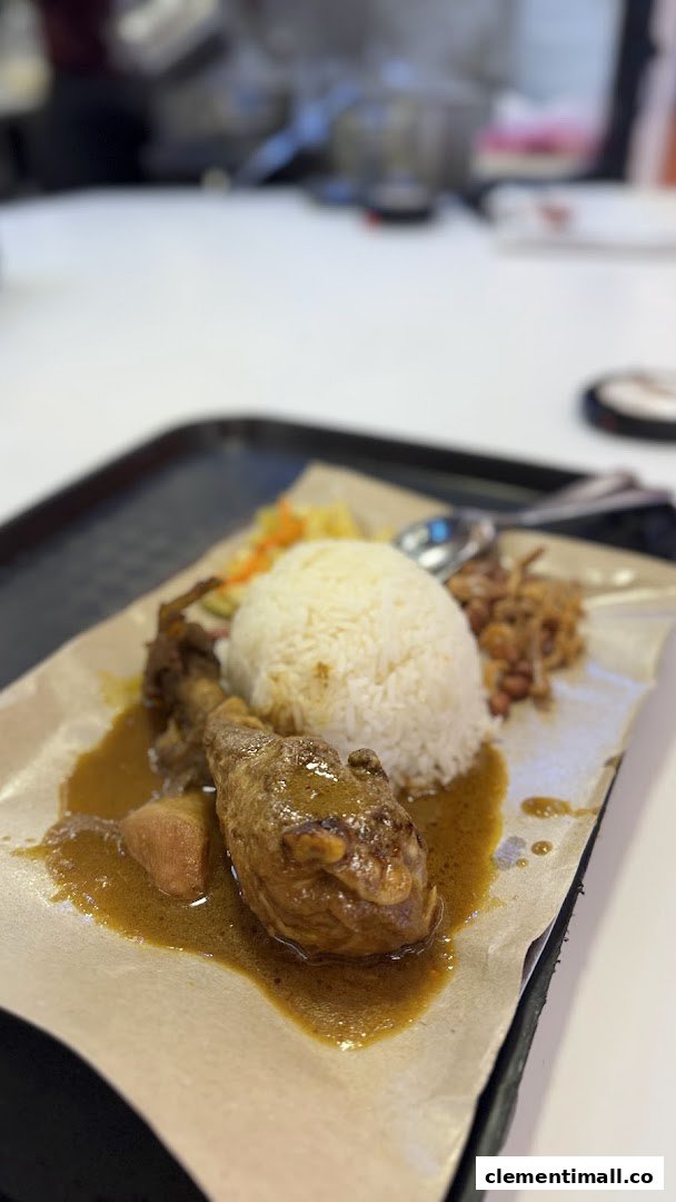 A delicious plate of chicken curry with rice and side dishes, served on a tray.