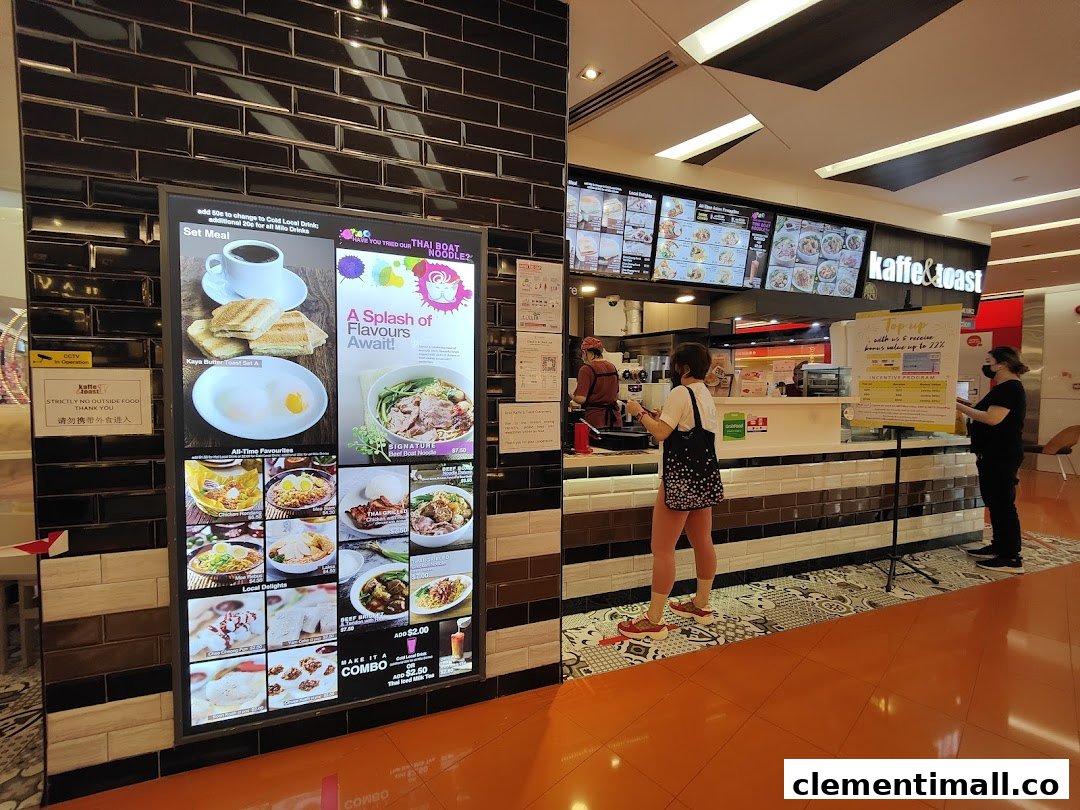 A food stall counter with digital menu boards displaying various Thai and local dishes, with customers ordering.