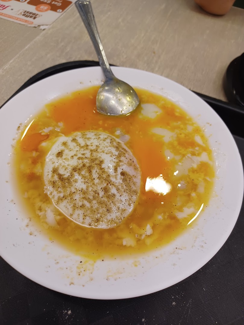 A close-up of a plate of soft-boiled eggs with a spoon, seasoned with pepper.