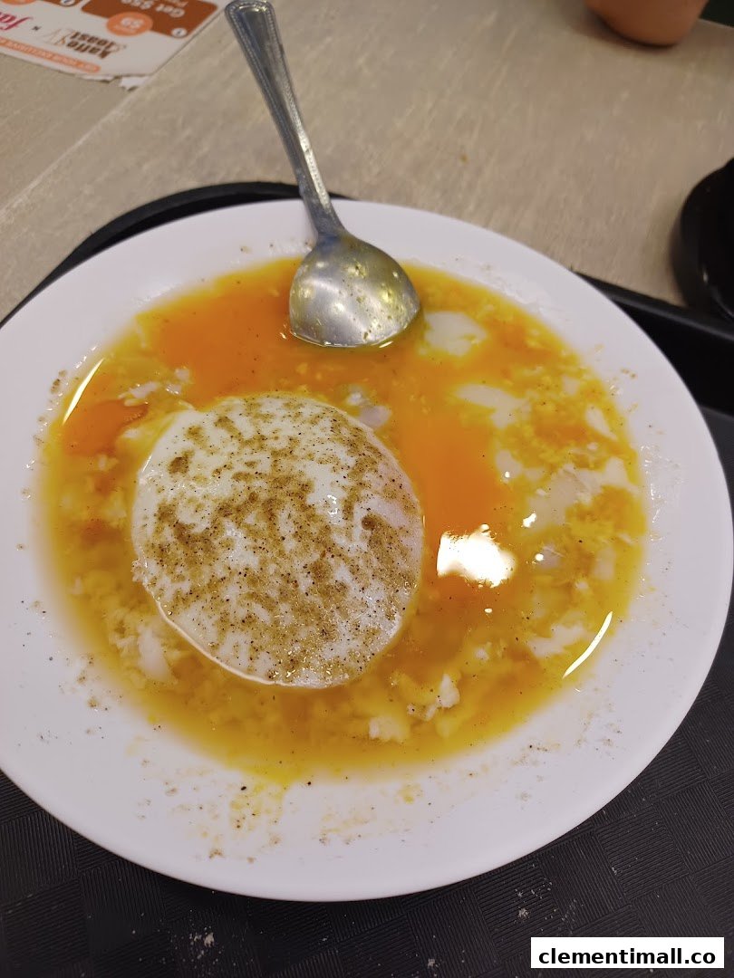 A close-up of a plate of soft-boiled eggs with a spoon, seasoned with pepper.