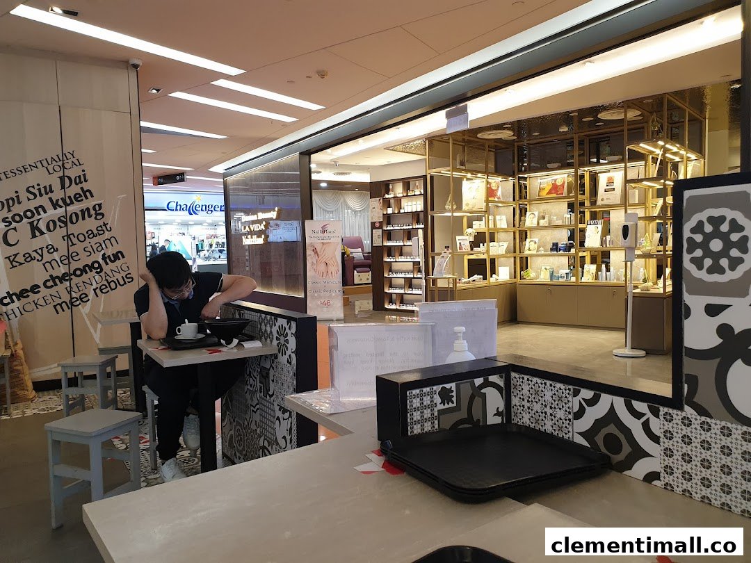 An interior shot of Kaffe Toast Thai Noodle Bar, showing a customer dining and adjacent mall shops.