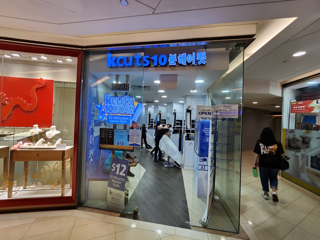 The glass storefront of kcuts hair salon, showcasing its interior with customers and promotional signage.