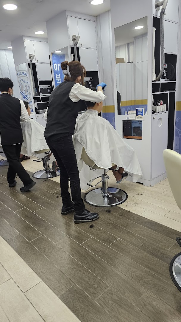 A stylist gives a haircut to a customer inside kcuts salon, showing the clean, modern interior.