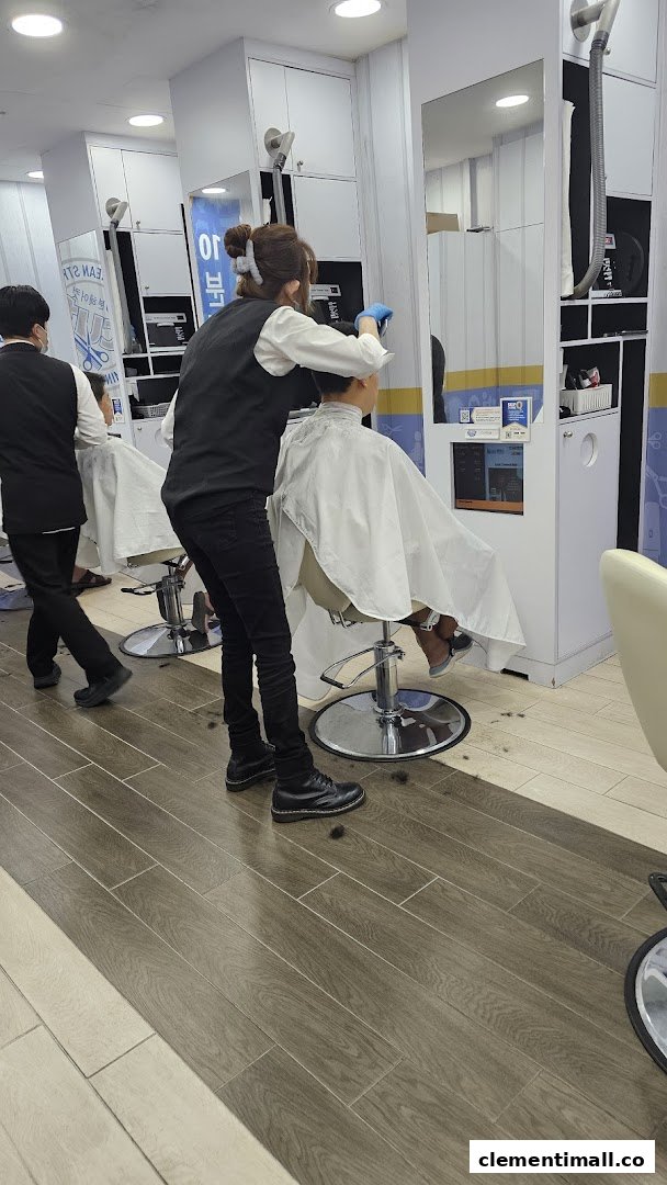 A stylist gives a haircut to a customer inside kcuts salon, showing the clean, modern interior.