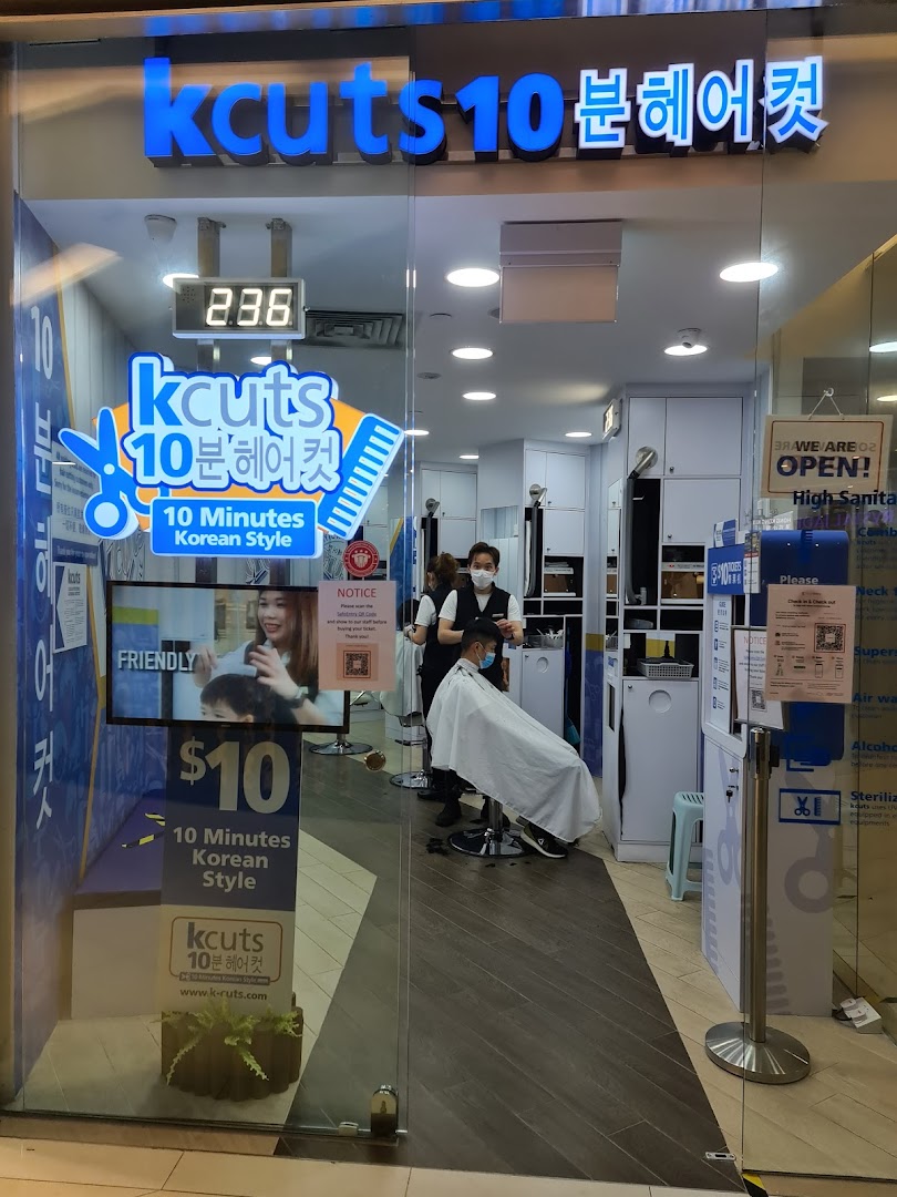The storefront of kcuts, a hair salon, showing a customer receiving a haircut inside.