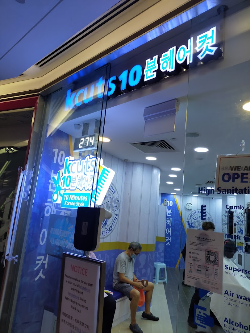The brightly lit storefront of kcuts, a Korean-style express haircut salon, with a customer waiting inside.