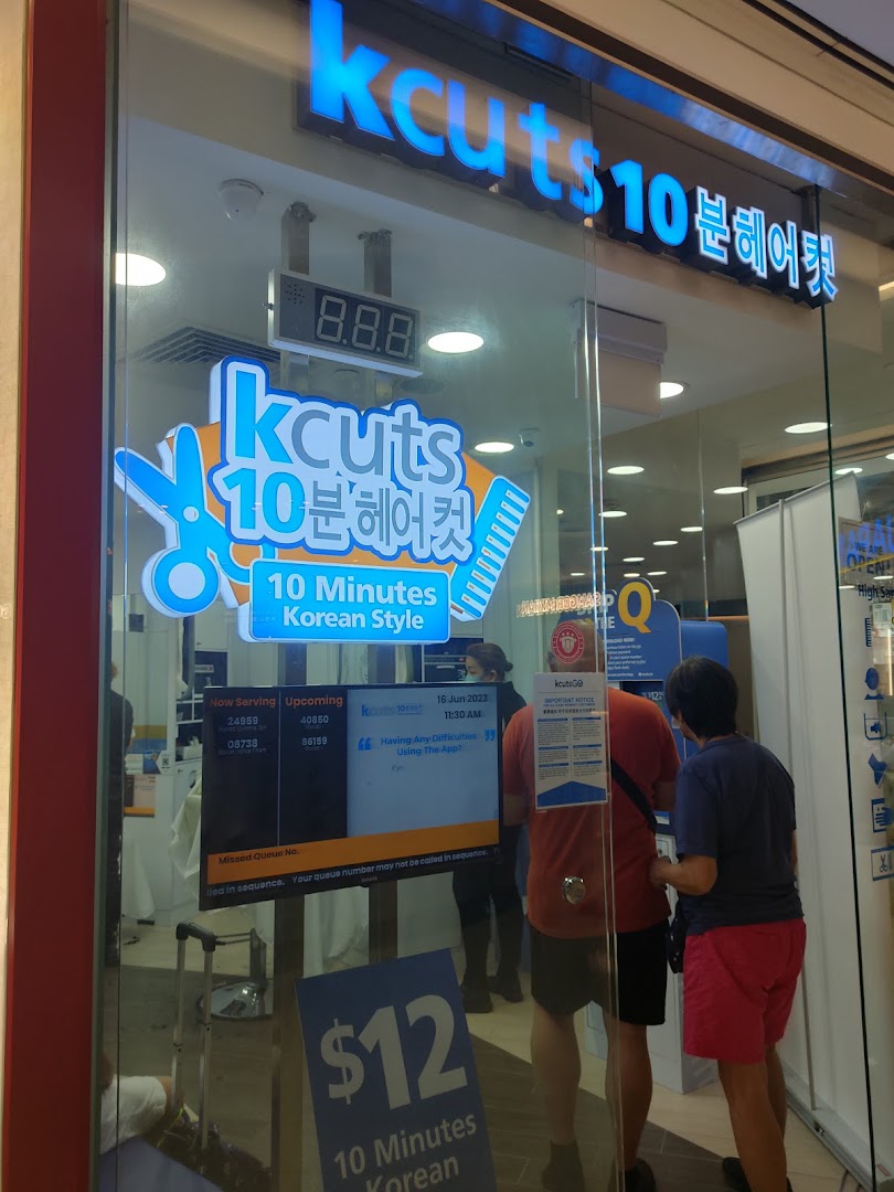 The storefront of kcuts, a hair salon offering 10-minute Korean style cuts, with customers inside.