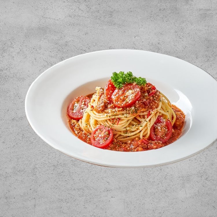 A close-up of a delicious plate of spaghetti bolognese with cherry tomatoes and parsley.