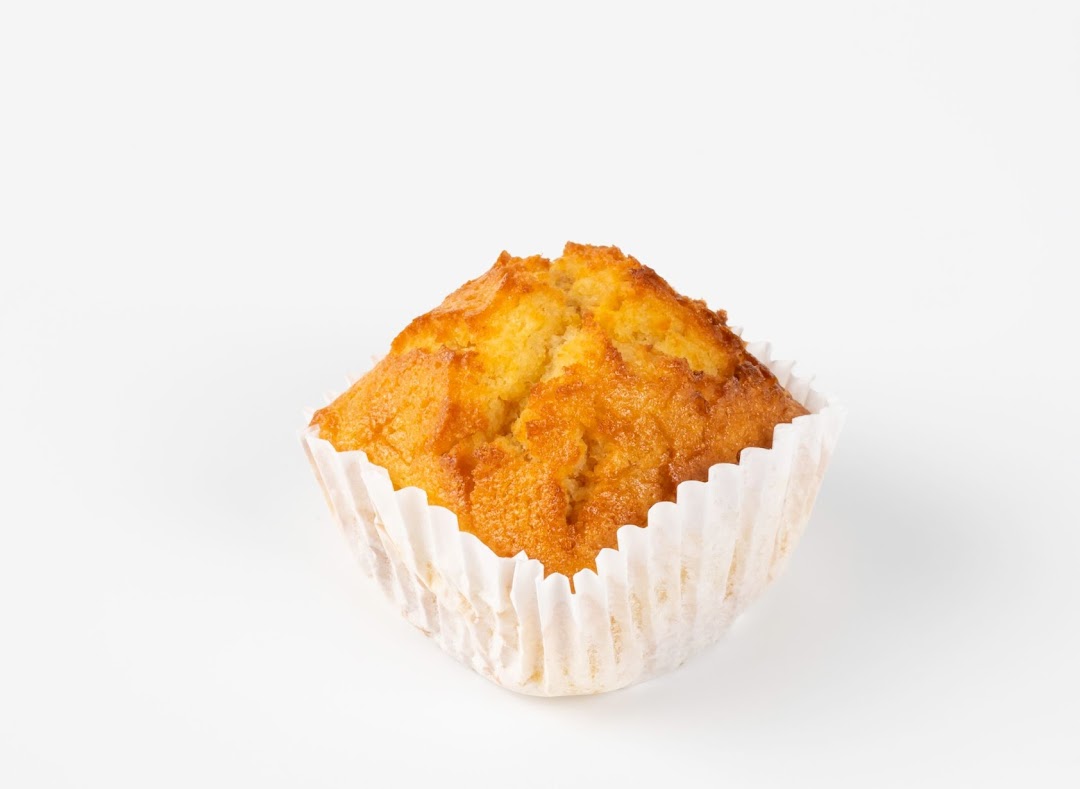 A single golden-brown muffin in a white paper liner, presented on a clean white background.