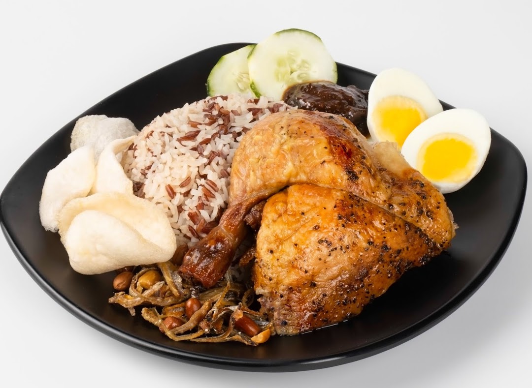 A delicious plate featuring roasted chicken, mixed rice, a boiled egg, cucumber, and crispy crackers.