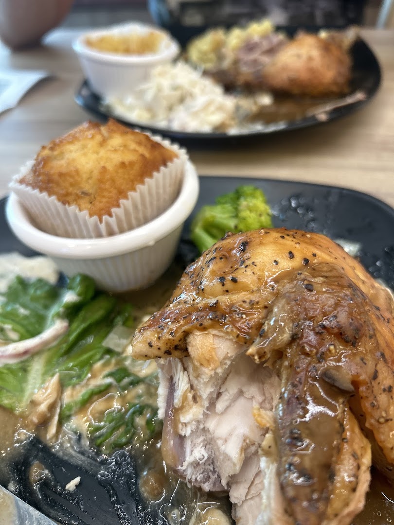 A close-up of a delicious roasted chicken meal with a muffin and sides from Kenny Rogers Roasters.