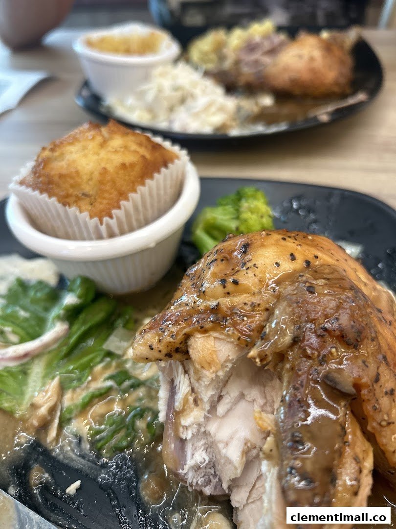 A close-up of a delicious roasted chicken meal with a muffin and sides from Kenny Rogers Roasters.
