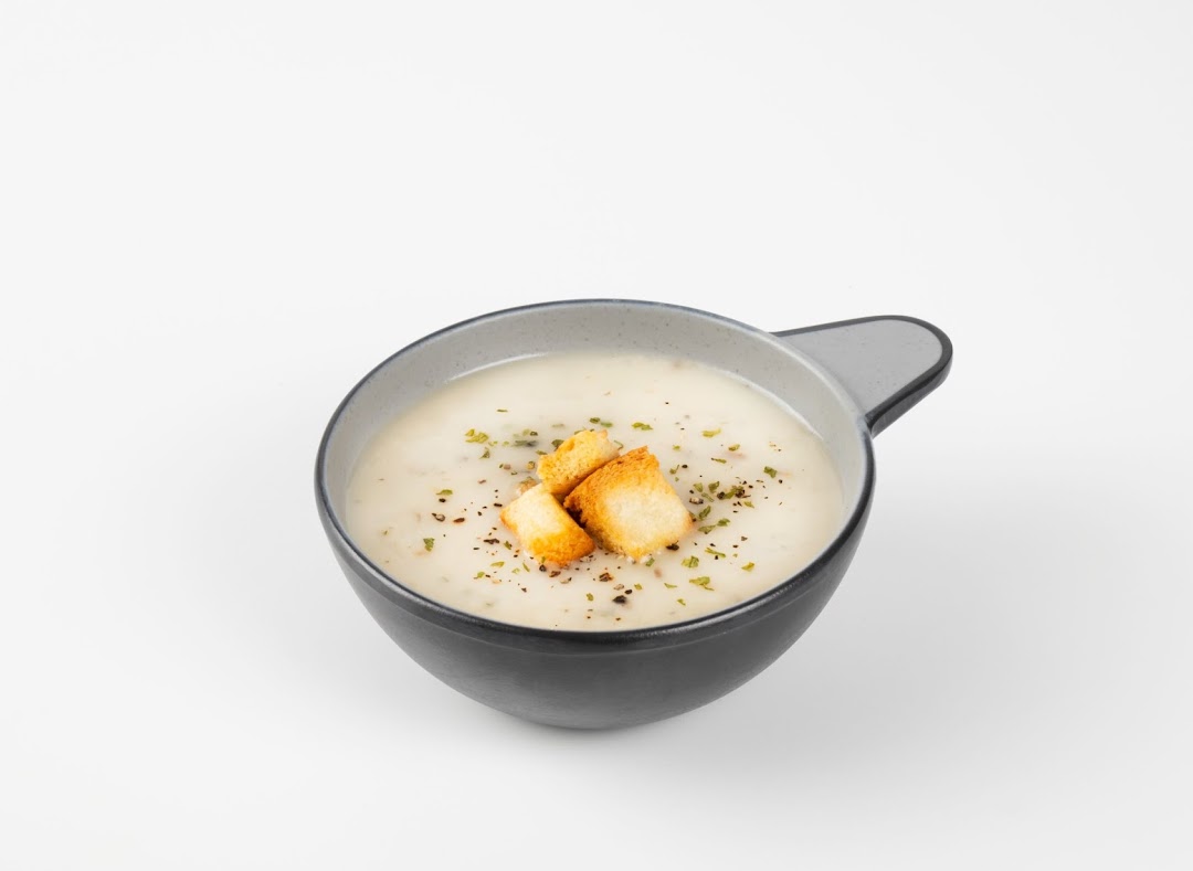 A creamy bowl of soup topped with golden croutons and fresh herbs.