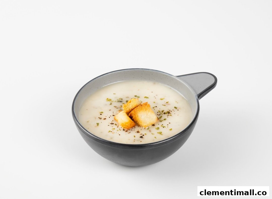 A creamy bowl of soup topped with golden croutons and fresh herbs.