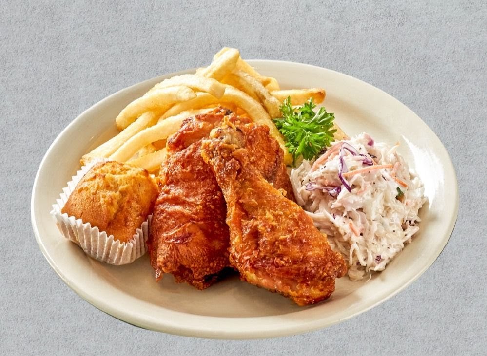 A plate featuring crispy fried chicken, golden fries, creamy coleslaw, and a corn muffin.