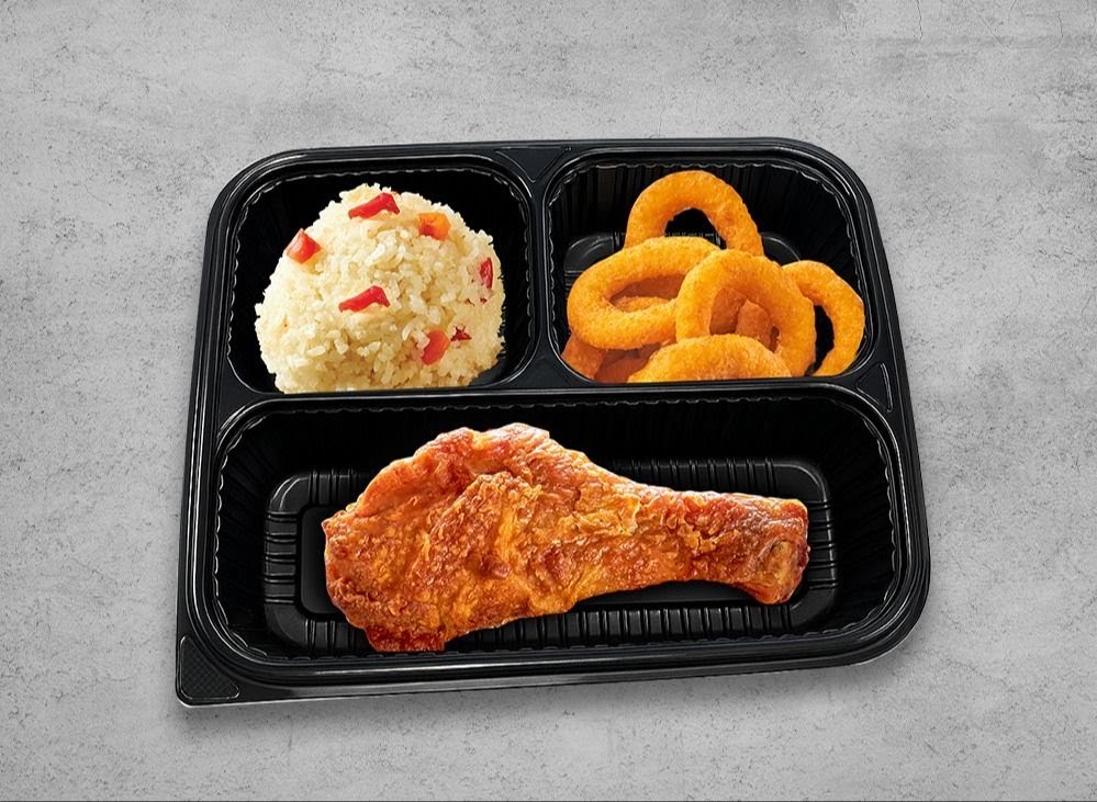 A partitioned meal container featuring fried chicken, rice with peppers, and golden onion rings.
