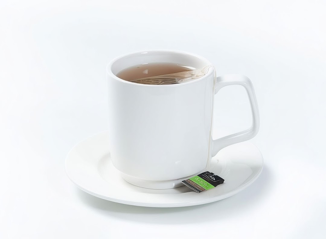 A white mug of hot tea with a tea bag on a saucer, ready to be enjoyed.