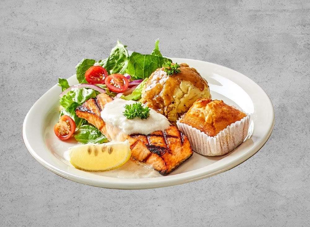 A plate featuring grilled salmon, mashed potatoes, a muffin, and a fresh salad.