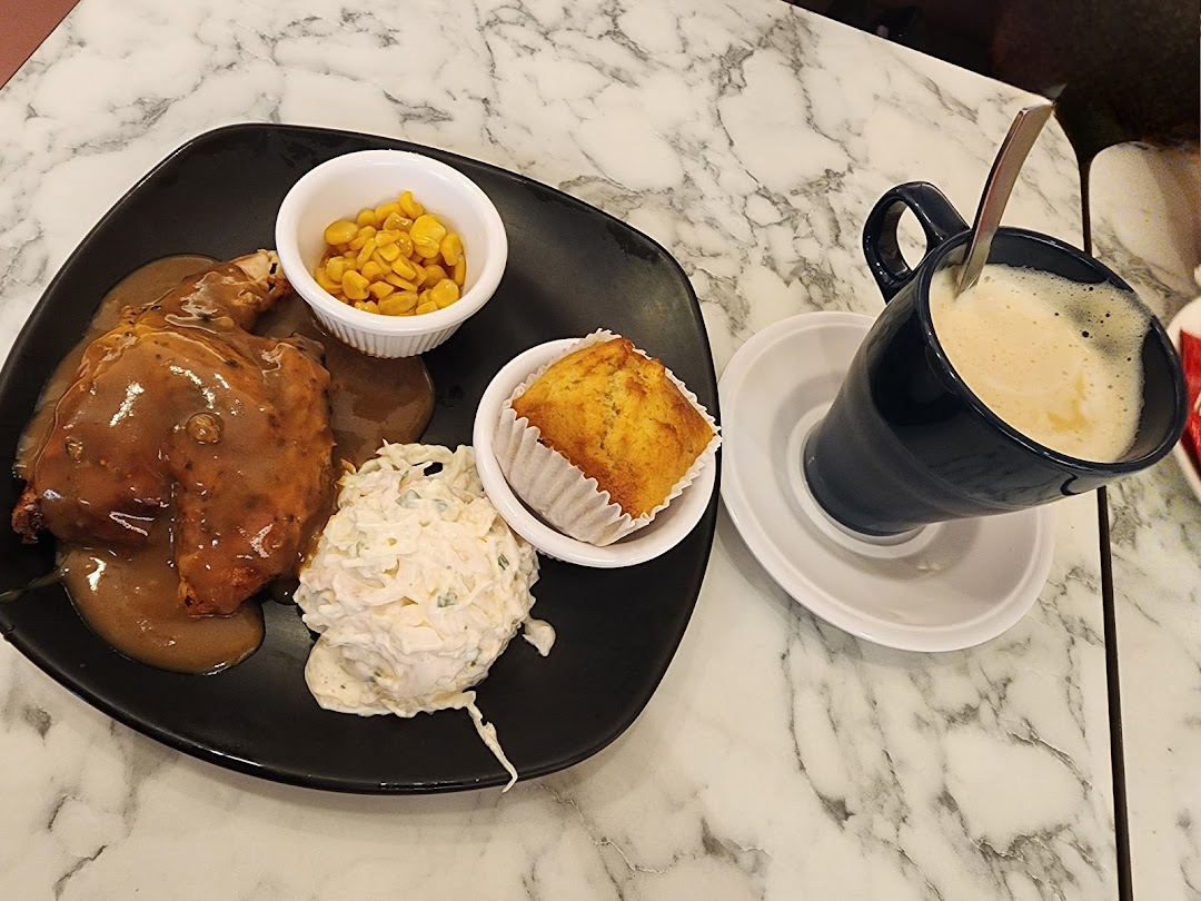 A delicious roasted chicken meal with sides and a hot beverage on a marble table.