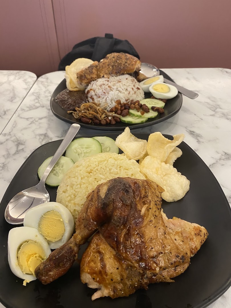 Two plates of delicious roasted chicken meals with rice, eggs, and various sides.