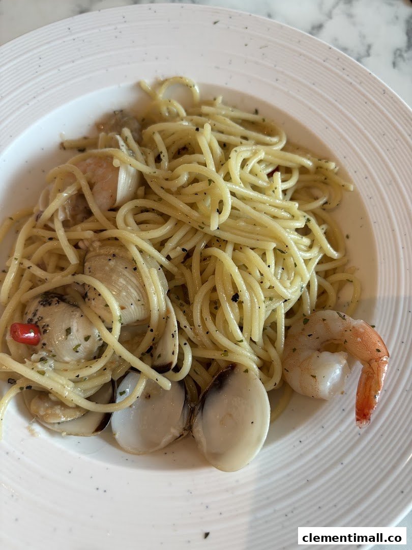 A close-up of a plate of spaghetti with clams, shrimp, and herbs.