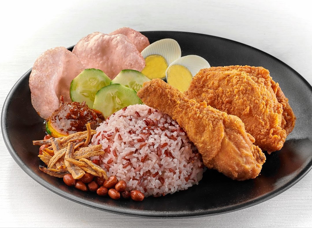 A delicious plate of Nasi Lemak with crispy fried chicken, rice, sambal, egg, peanuts, anchovies, and crackers.