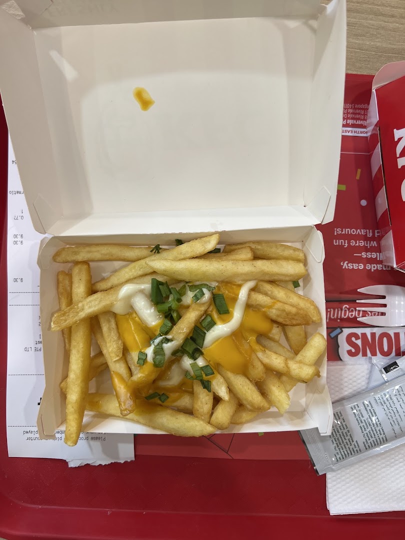 A close-up of golden french fries topped with melted cheese, mayonnaise, and fresh green onions.