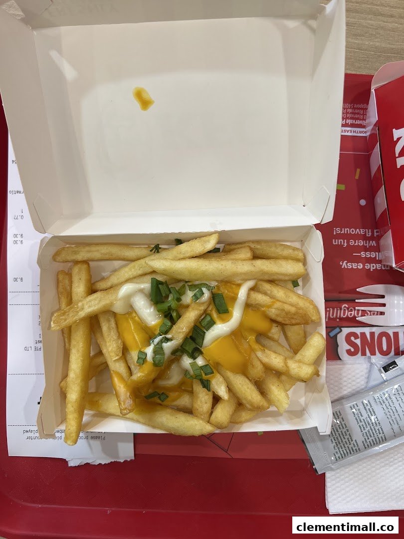 A close-up of golden french fries topped with melted cheese, mayonnaise, and fresh green onions.