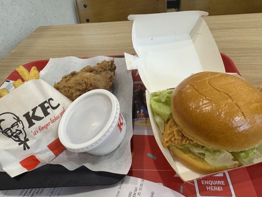 A delicious KFC meal featuring fried chicken, a burger, fries, and sauce on a red tray.