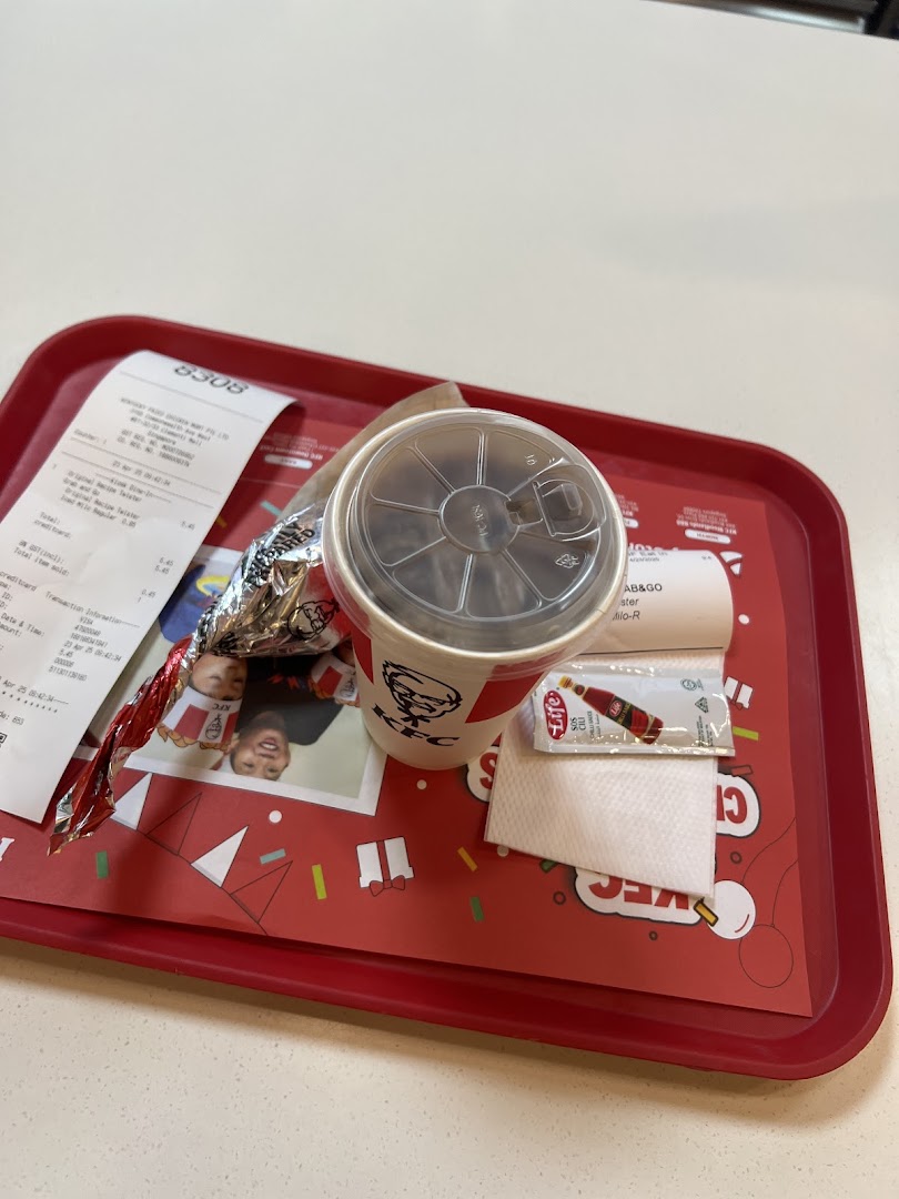 A KFC meal with a drink, wrapped food, and receipt on a festive red tray.