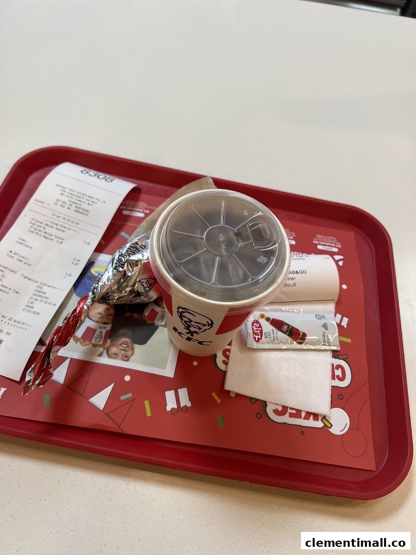 A KFC meal with a drink, wrapped food, and receipt on a festive red tray.