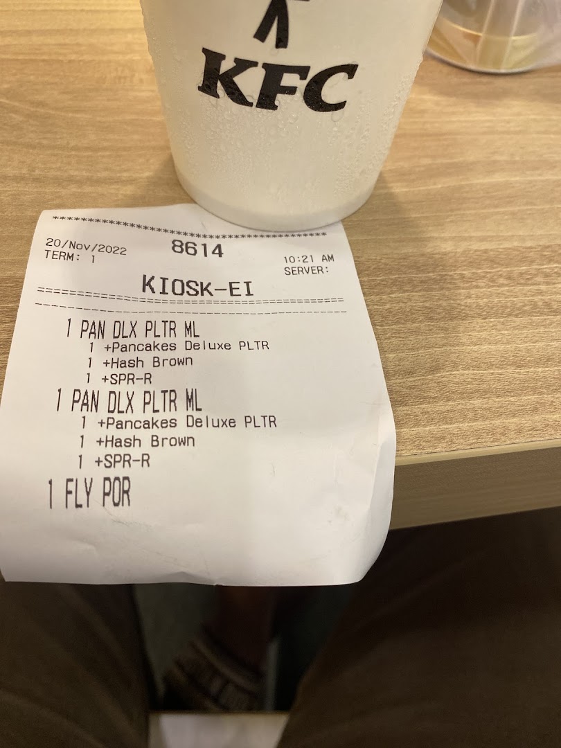 A KFC receipt showing breakfast items and a condensation-covered KFC cup on a wooden table.