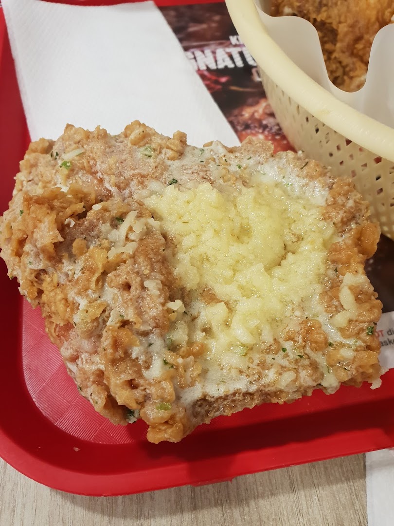 Close-up of a crispy fried chicken piece with a generous topping, served on a red tray.