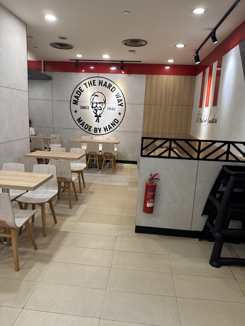 A clean and modern interior dining area of KFC, featuring tables, chairs, and the iconic Colonel Sanders logo.