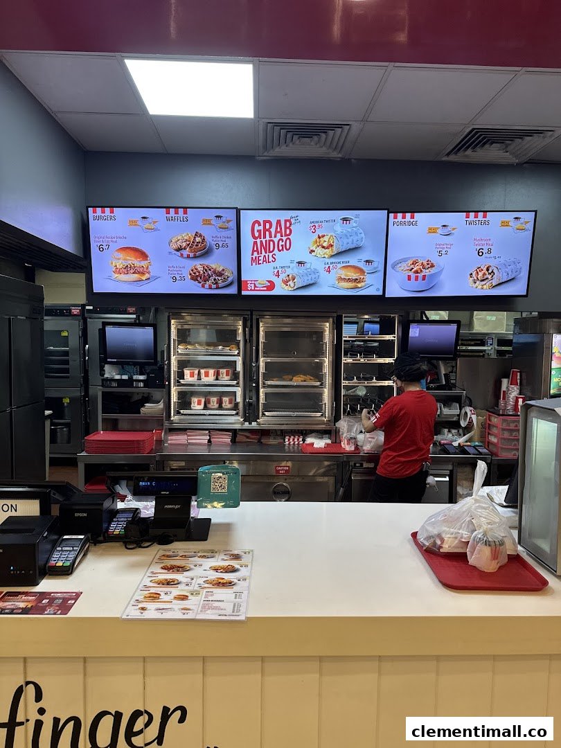 Interior view of KFC Clementi Mall featuring digital menu boards and a staff member at the counter.