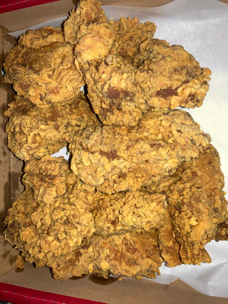 A close-up view of crispy, golden-brown fried chicken pieces in a takeout box.