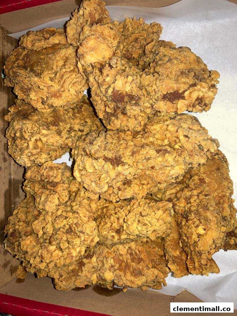 A close-up view of crispy, golden-brown fried chicken pieces in a takeout box.