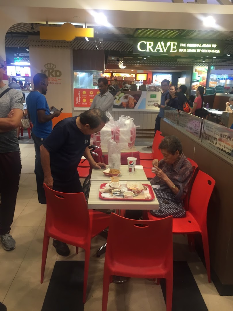 Customers enjoy meals at tables with red chairs in a bustling food court, with other eateries visible.