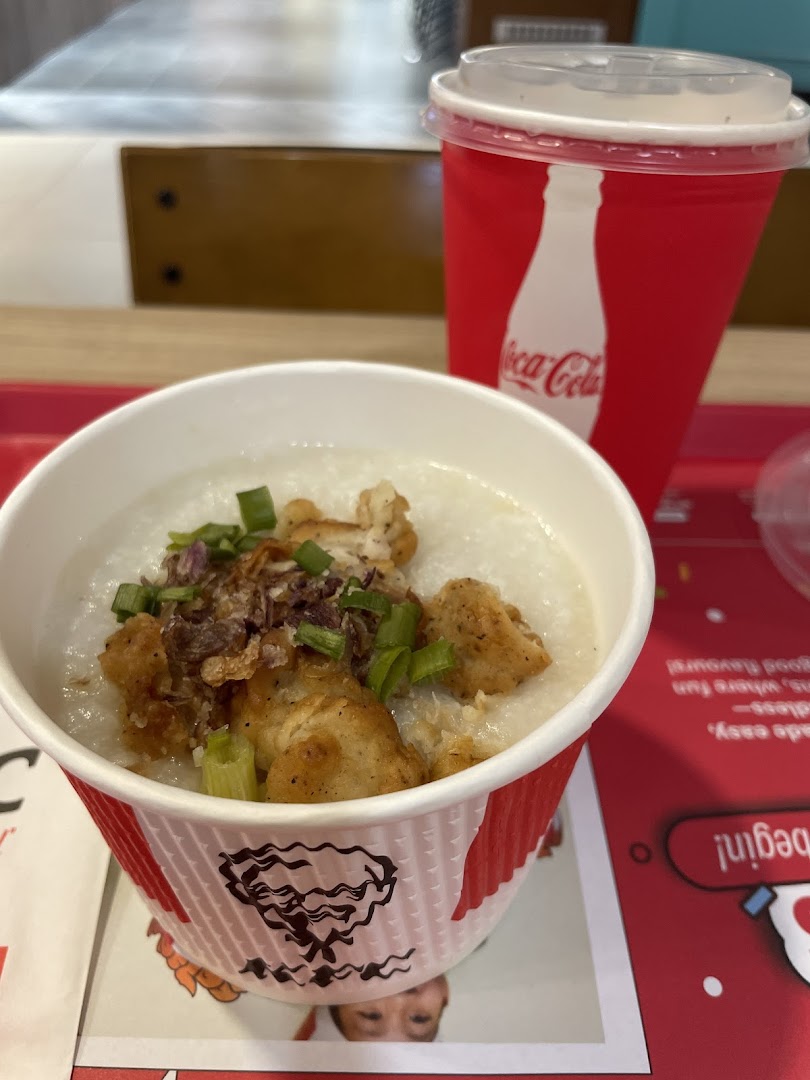 A close-up of KFC's chicken porridge and a Coca-Cola drink on a red tray.