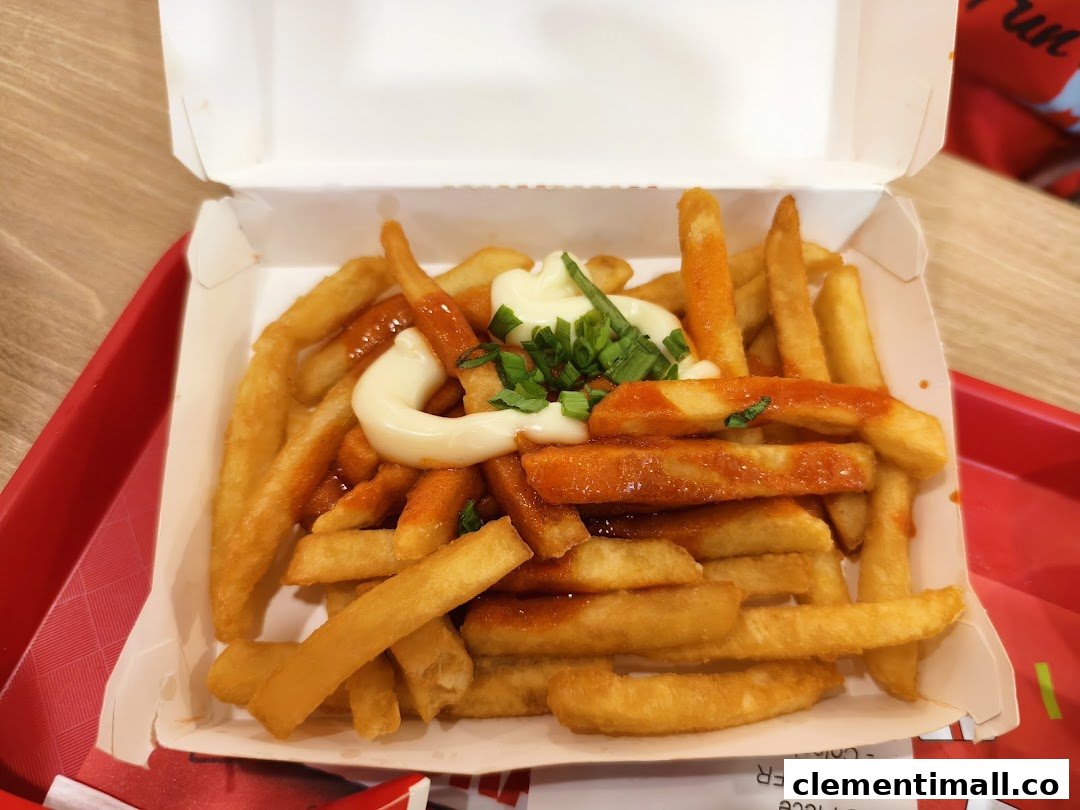 A close-up of KFC's golden fries topped with spicy sauce, creamy mayonnaise, and fresh spring onions.