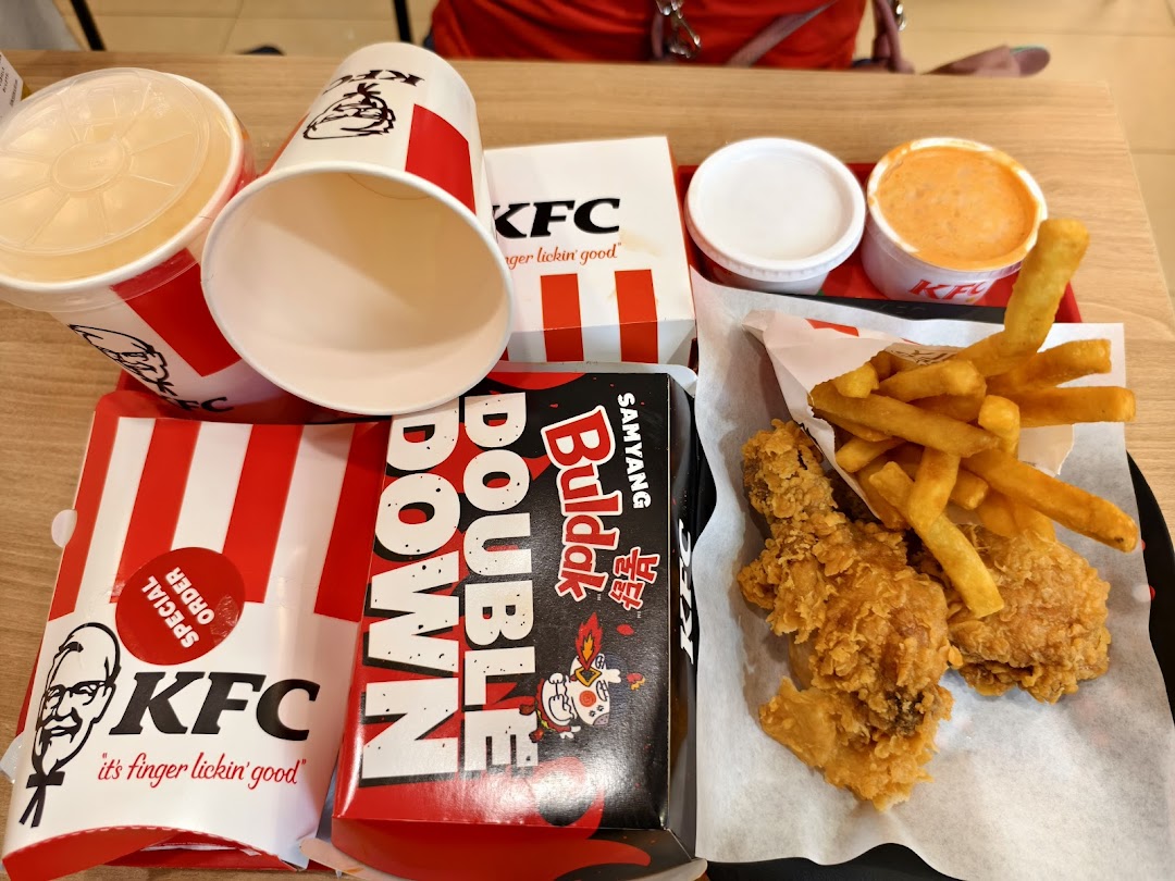 A table filled with a KFC meal, including fried chicken, fries, drinks, and a Double Down.