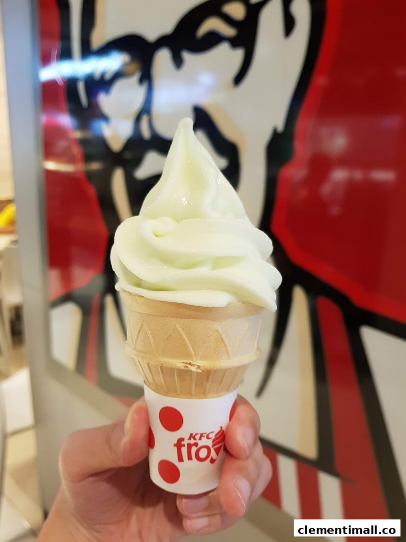 A hand holds a refreshing KFC froyo soft-serve ice cream cone inside the restaurant.