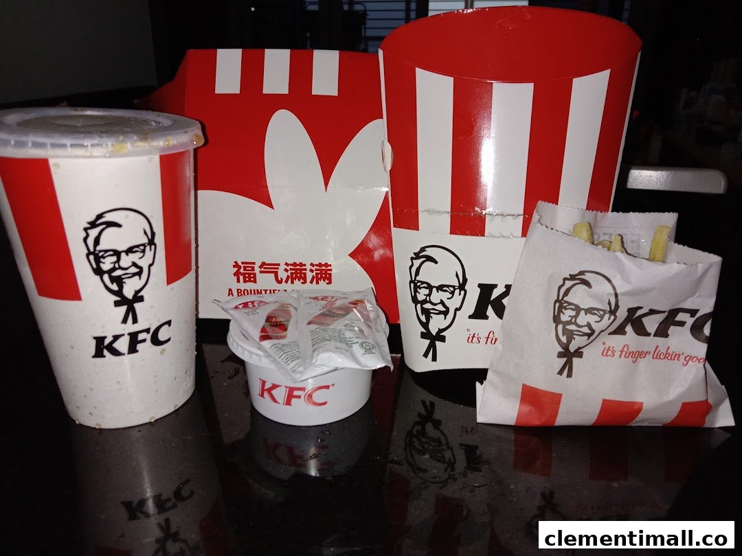 A close-up of various KFC food items, including a drink, fries, and chicken packaging.