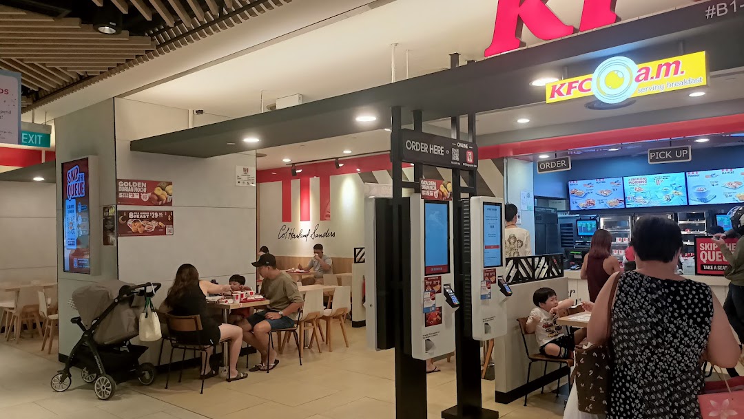Customers dine and order at self-service kiosks inside a busy KFC restaurant.