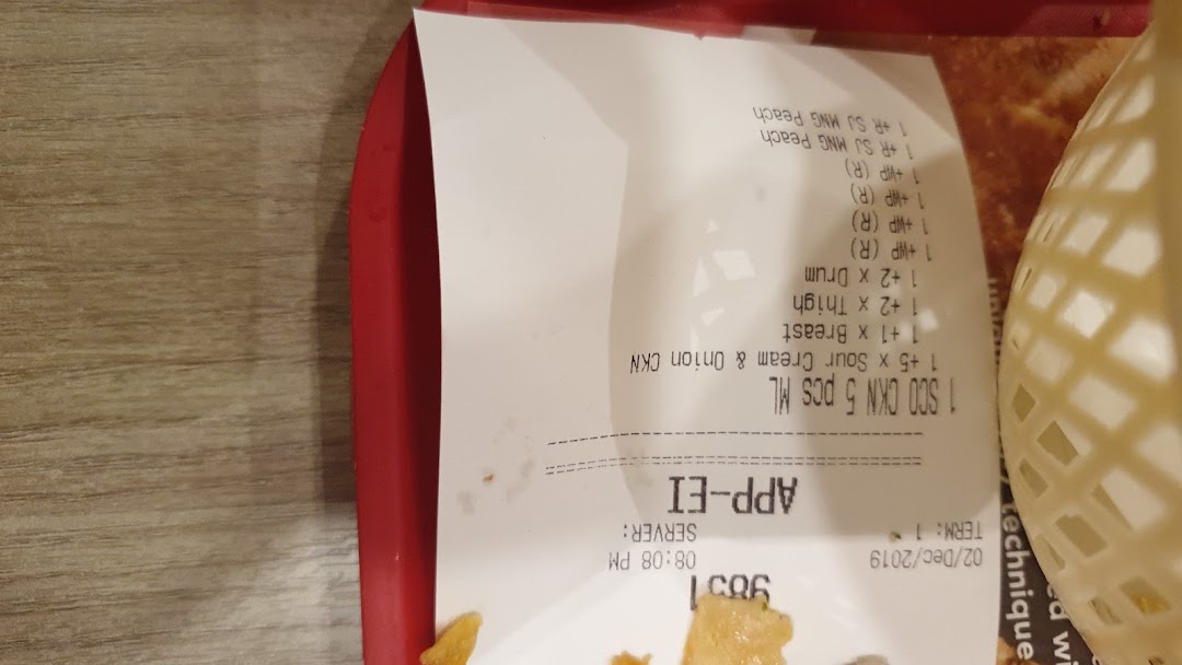 A close-up of a KFC receipt on a red tray, showing purchased items and order details.