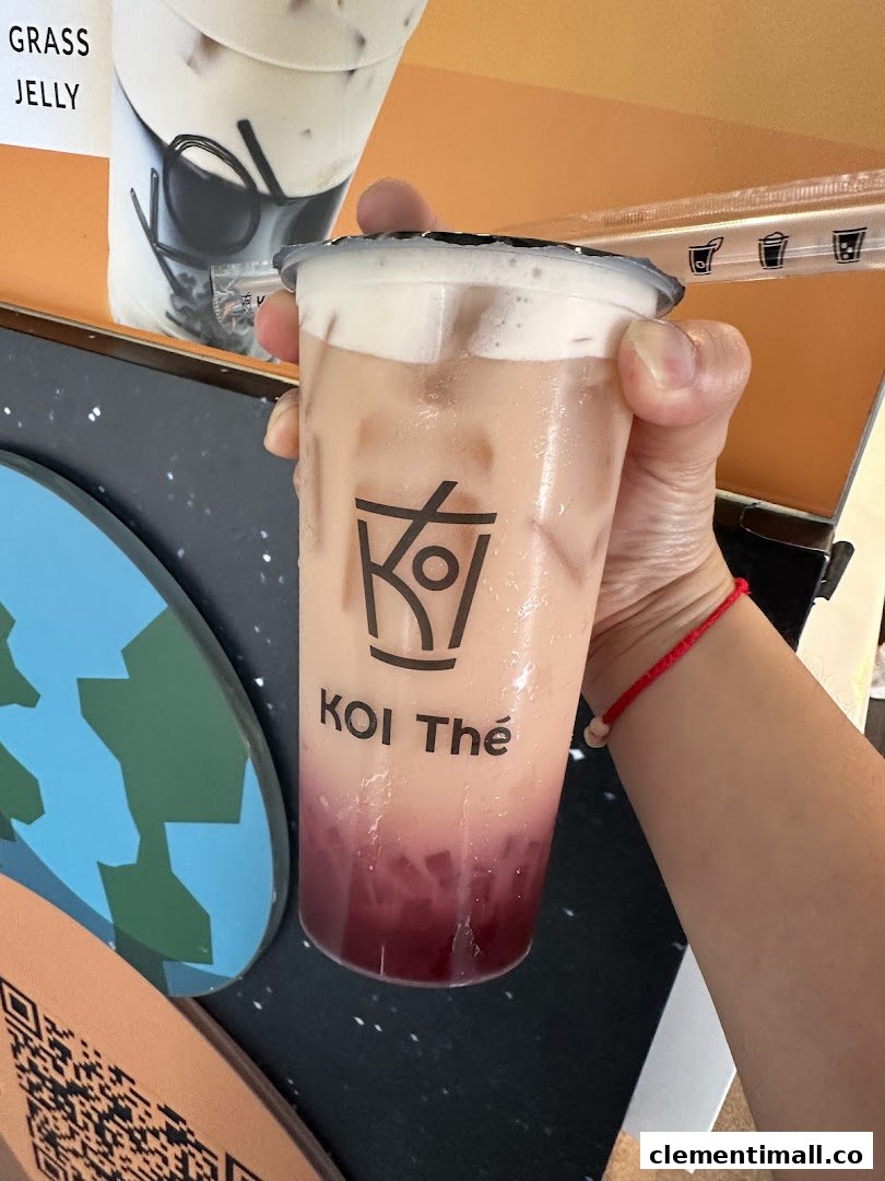 A hand holds a refreshing KOI Thé bubble tea with a creamy top layer and red jelly.
