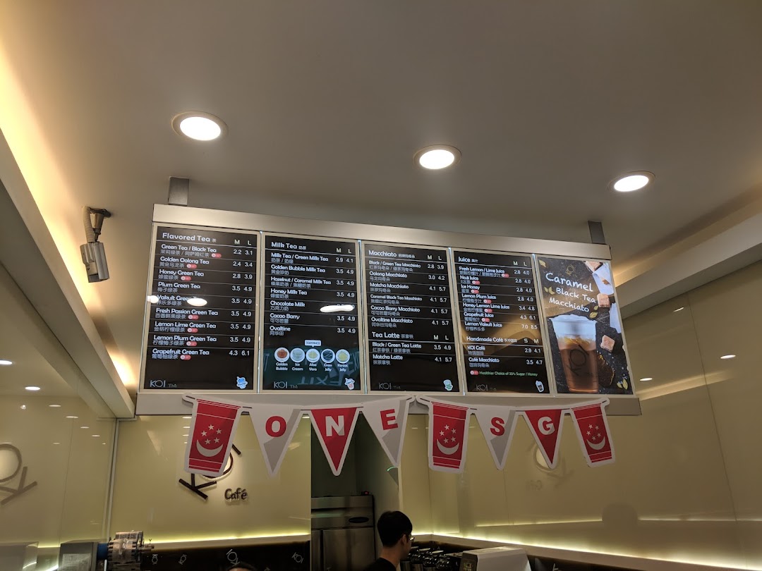 A large digital menu board displaying various tea and juice options at KOI Thé.